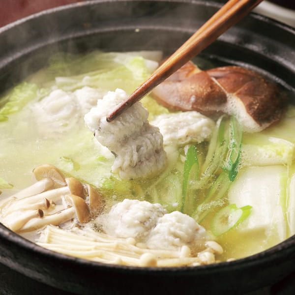 土鍋で煮込まれた白身魚と野菜。湯気が立ち上る温かい鍋料理。