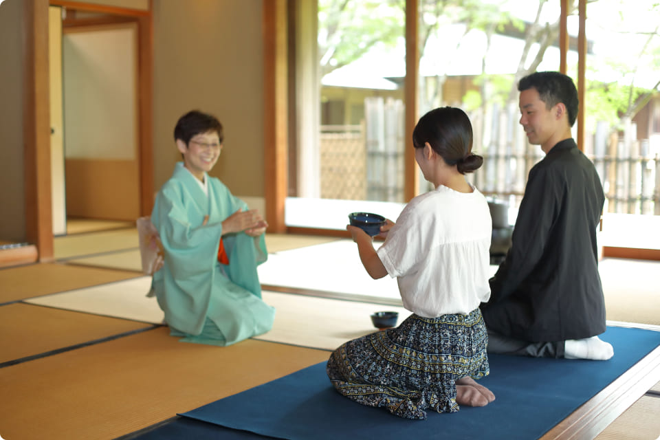 茶道を学ぶ人々が茶室で丁寧に指導を受けている様子。